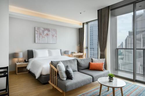 a hotel room with a bed and a couch at Oakwood Suites Bangkok in Bangkok