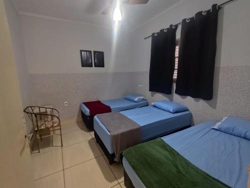 a room with two beds and a chair in it at Casa Prox Centro in Ribeirão Preto