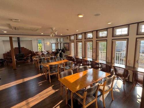 a restaurant with wooden tables and chairs and windows at Pension Lavender in Furano