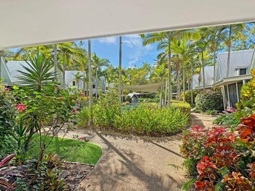 a garden with flowers and trees and houses at Canopy Chalet 6 in Nelly Bay