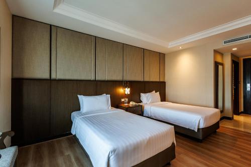 a hotel room with two beds and a night stand at Al Meroz Hotel Bangkok - The Leading Halal Hotel in Bangkok