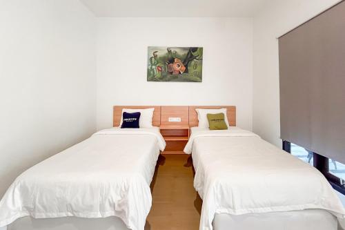 three beds in a room with white walls at Urbanview Hotel Syariah Nawasena Guest House IKN by RedDoorz in Sepaku