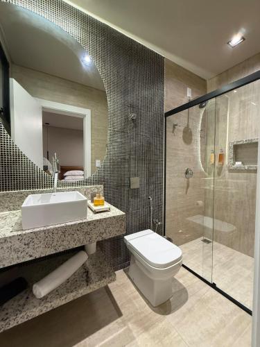 a bathroom with a sink and a toilet and a shower at Suite Boutique 102 Cheia de Graça in Divinópolis