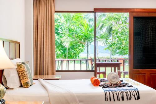 a bedroom with a bed and a large window at Sailom Resort Bangsaphan in Bang Saphan
