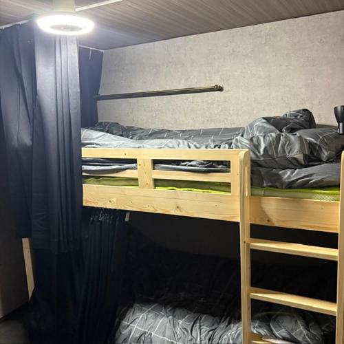 a bedroom with a bunk bed with a ladder to the top at ゲストハウスヤドカリ in Nanao