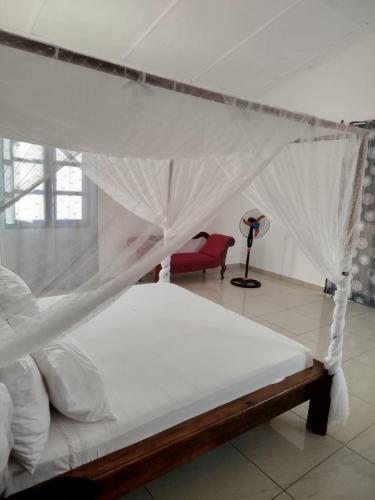 a bedroom with a canopy bed and a red chair at Castello in Anakao