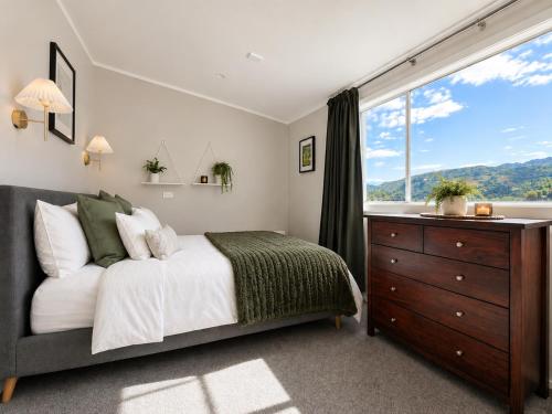 a bedroom with a bed and a large window at The Nelson Lookout - Mountain Views & City Centre Living in Nelson
