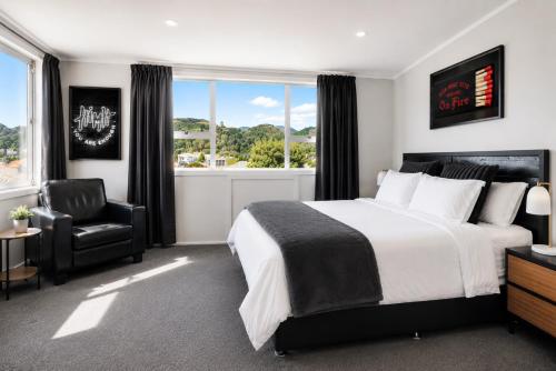 a bedroom with a bed and a chair and a window at The Nelson Lookout - Mountain Views & City Centre Living in Nelson