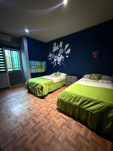 a bedroom with two beds and a blue wall at Casa en Tepic in Tepic