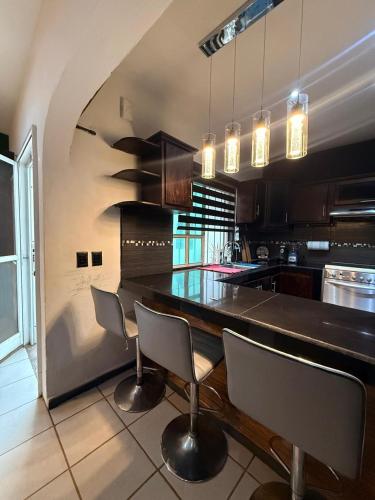a kitchen with a bar with chairs and a table at Casa en Tepic in Tepic