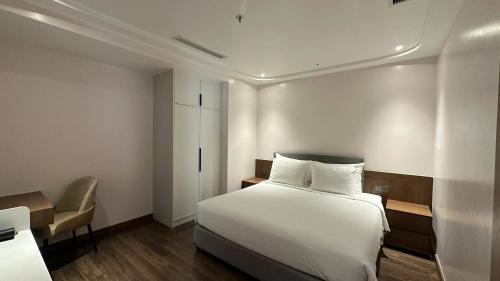 a bedroom with a white bed and a chair at The Dome Grand in Ninh Lão