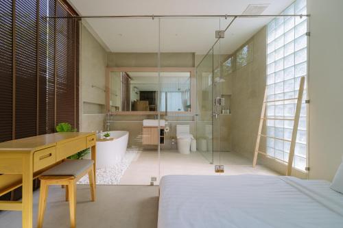 a bathroom with a glass walled shower and a bed and a desk at Radarin Villa in Ban Khao Kloi
