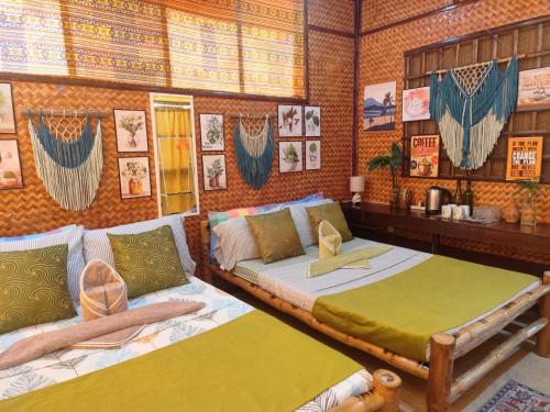 two beds in a room with pictures on the wall at Amwani Garden Pool & Kubo in Puerto Princesa City