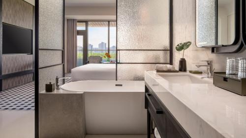 a bathroom with a white sink and a bed at Kimpton Nine Trees Shanghai by IHG in Shanghai