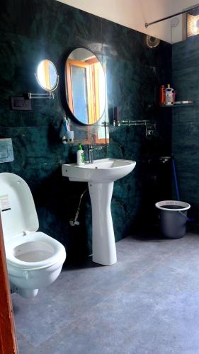 a bathroom with a toilet and a sink and a mirror at Falak Stays in Shamshi