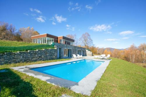 a house with a swimming pool and a stone wall at Villa Intelvi in Castiglione dʼIntelvi