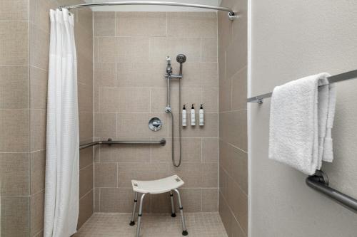 a shower with a white chair in a bathroom at SpringHill Suites Dallas Arlington North in Arlington