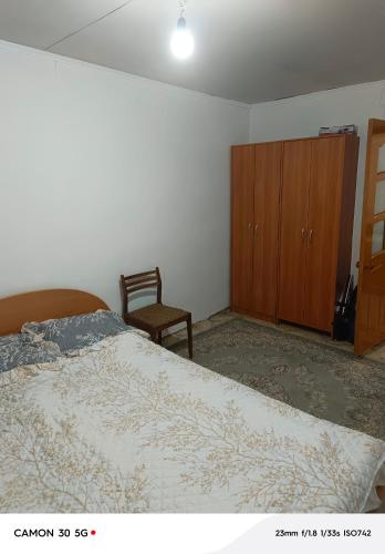 a bedroom with a bed and a wooden cabinet at Сдается дача in Balqash