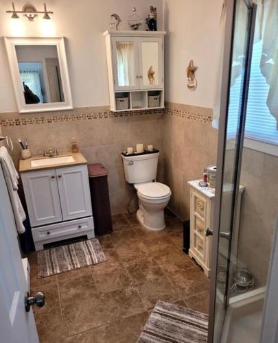 a bathroom with a toilet and a sink and a mirror at Cozy Condo in Seaside Heights