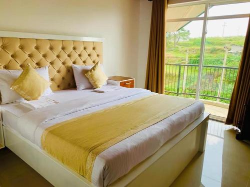 a bedroom with a large bed with a large window at Lake Infinity Luxury Condos in Nuwara Eliya