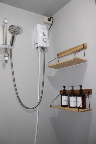 a bathroom with a shower and a shelf with bottles at Charlotte place in El Nido