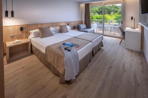 a bedroom with a large bed and a large window at GHT Oasis Tossa & Spa in Tossa de Mar