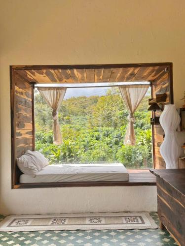 a window in a room with a bed in front at Đồi Ông Thoại Cottage in Bảo Lộc