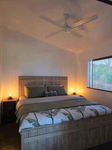 a bedroom with a bed with a ceiling fan at Hideaway Falls Rustic Farm House in Ravenshoe