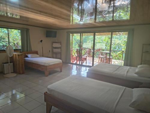 a bedroom with two beds and a balcony at Drake Bay Corcovado The Monkey Trail in Drake