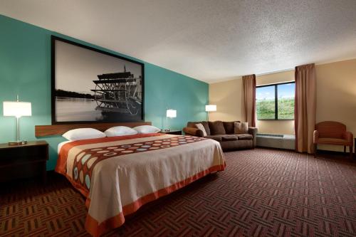 a hotel room with a large bed and a couch at Super 8 by Wyndham Peoria East in Peoria
