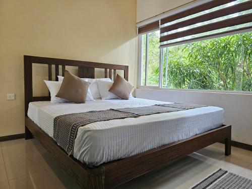a bed in a bedroom with a large window at Sunrise Staycation in Katuneriya