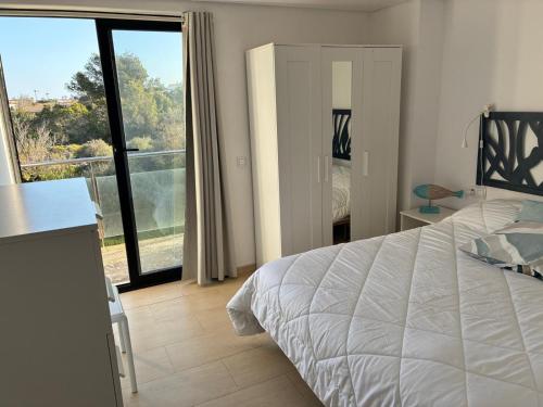 a bedroom with a white bed and a balcony at Apartamento Sa Perdiu 16 in Son Carrio