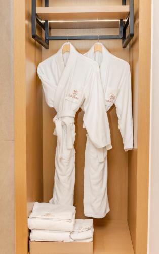 a closet with white shirts and towels on a rack at Jiuding Joy Hotel in Kathmandu