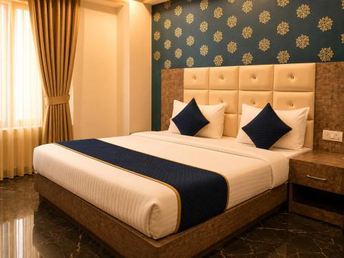 a bedroom with a large bed with blue and white pillows at Hotel Hyfa Continental in Lucknow