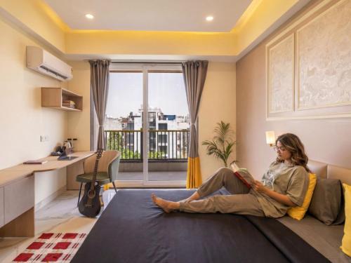 a woman sitting on a couch reading a book at The Hosteller Gurgaon in Gurgaon