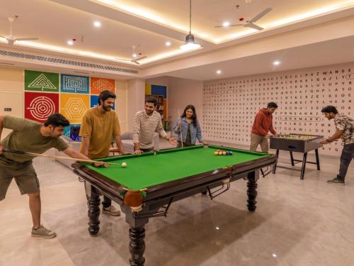 a group of people playing billiards in a room at The Hosteller Gurgaon in Gurgaon