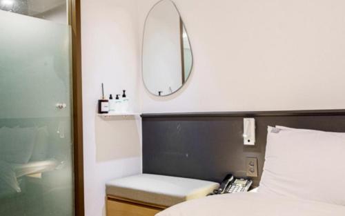 a bedroom with a bed with a mirror and a phone at 넘버25 신촌점 in Seoul