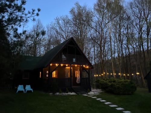 a cabin in the woods at night with lights at Domek Pod Lasem in Trzciana