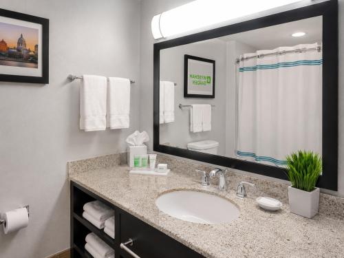 a bathroom with a sink and a large mirror at Wyndham Garden OKC Airport - Event Center, Indoor pool, Arcade Near Paycom, Fairgrounds in Oklahoma City