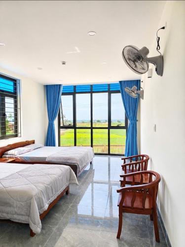 a bedroom with two beds and a chair and a window at Mom's house Lý Sơn in An Vĩnh Phướng