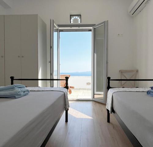 two beds in a room with a view of the ocean at Rosalie Home - Aegean Poseidon in Tinos