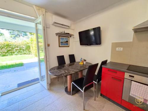 a kitchen with a table with chairs and a tv on the wall at Riverside Apartments - pet friendly in Sečovlje