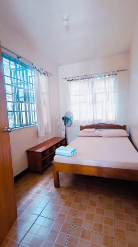 a bedroom with a large bed and two windows at Sanctuary Transient House Bacolod in Bacolod