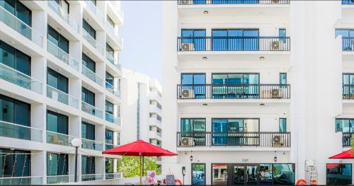 an apartment building with red umbrellas in front of it at Golden Sands Hotel Apartments in Dubai