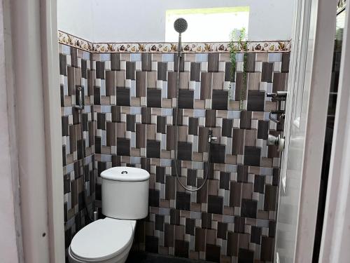 a bathroom with a toilet and a tile wall at Sanghiang Homestay in Batukaras