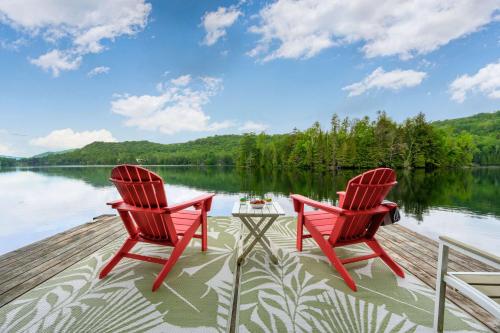 two red chairs and a table on a dock next to a lake at Spa Game room Waterfront - Le Refuge Vert in Brébeuf