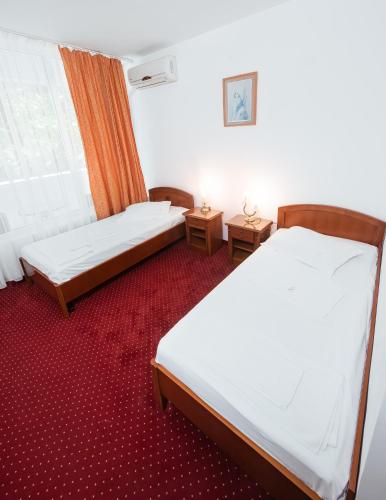 dwa łóżka w pokoju z czerwonym dywanem w obiekcie Hotel Scoica w mieście Jupiter