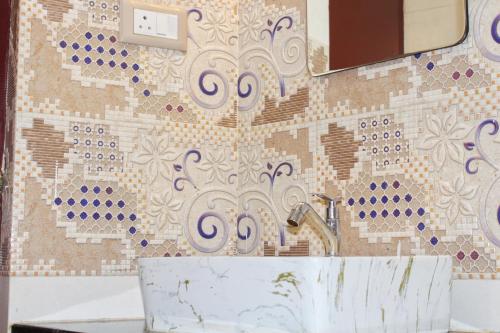 a bathroom with a sink and a mosaic wall at Altiora Homestay in Kodaikānāl