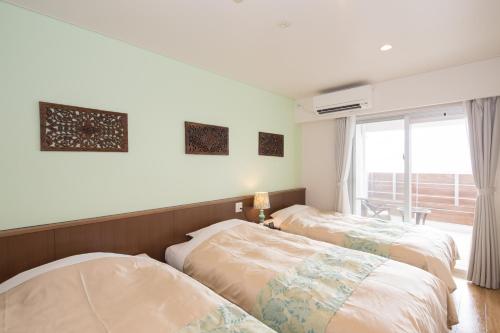 two beds in a room with a window at Hillside Sea View Resort Villa Gushikumui in Motobu