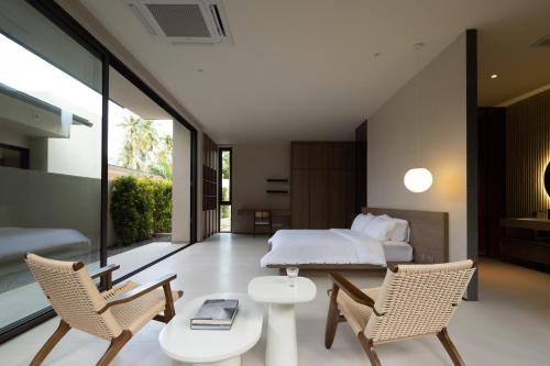 a bedroom with a bed and two chairs and a table at KW3 Villas in Mae Nam